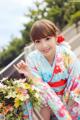 A woman in a kimono holding a bunch of flowers.