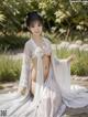 A woman in a white kimono sitting on the ground.