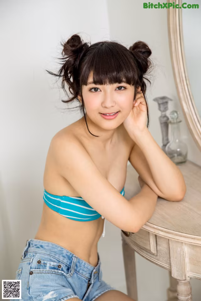A woman in a blue and white striped bikini sitting on a table.