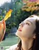 A woman holding a leaf in front of her face.