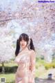 A woman in a pink lingerie standing in front of a tree.