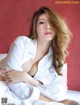 A woman laying on top of a bed in a white shirt.