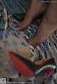 A pair of black pantyhose and red and black high heels on a rug.