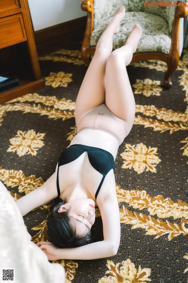 A woman laying on the floor in a black lingerie.