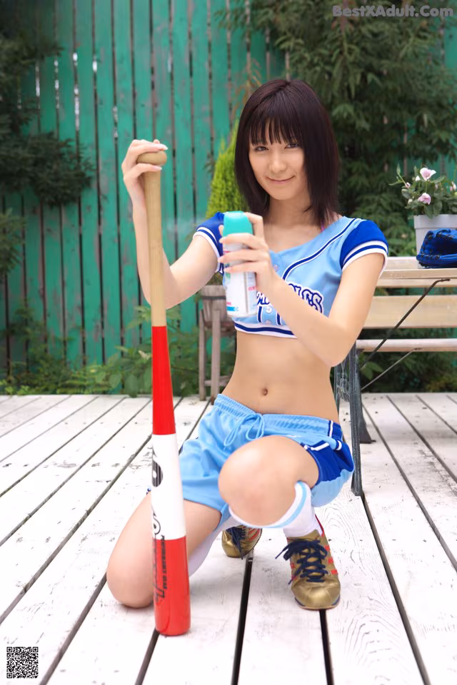 A woman in a blue and white uniform holding a baseball bat.