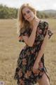 A woman in a floral dress standing in a field.