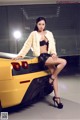 A woman sitting on top of a yellow sports car.