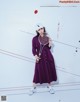 A woman in a purple dress holding a tennis racket.