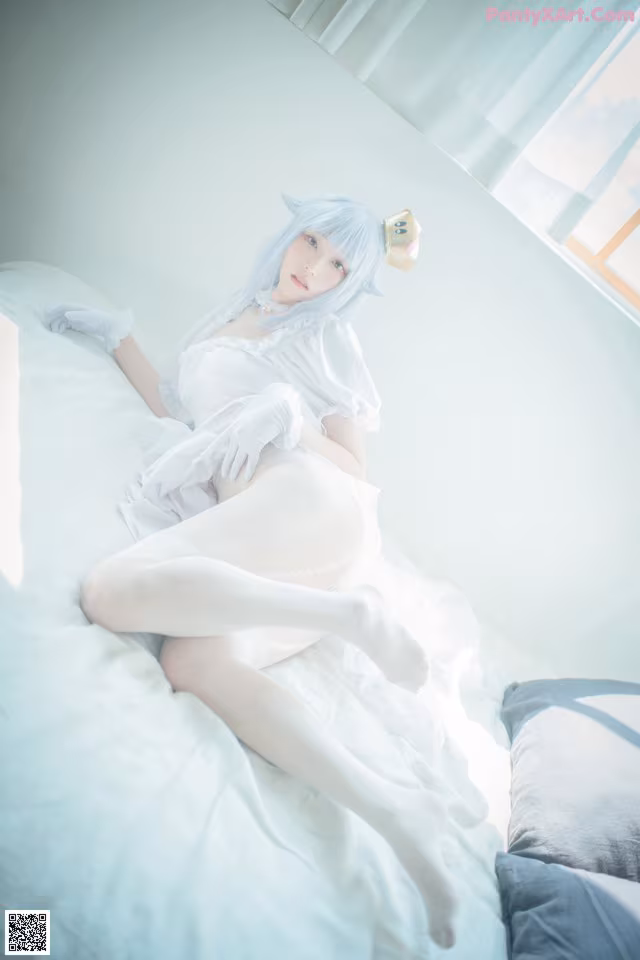 A woman in a white dress laying on a bed.