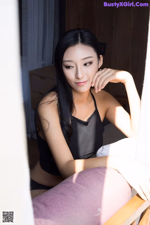 A woman sitting on top of a bed next to a window.