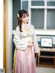 A woman in a pink and white hanbok standing in front of a computer.