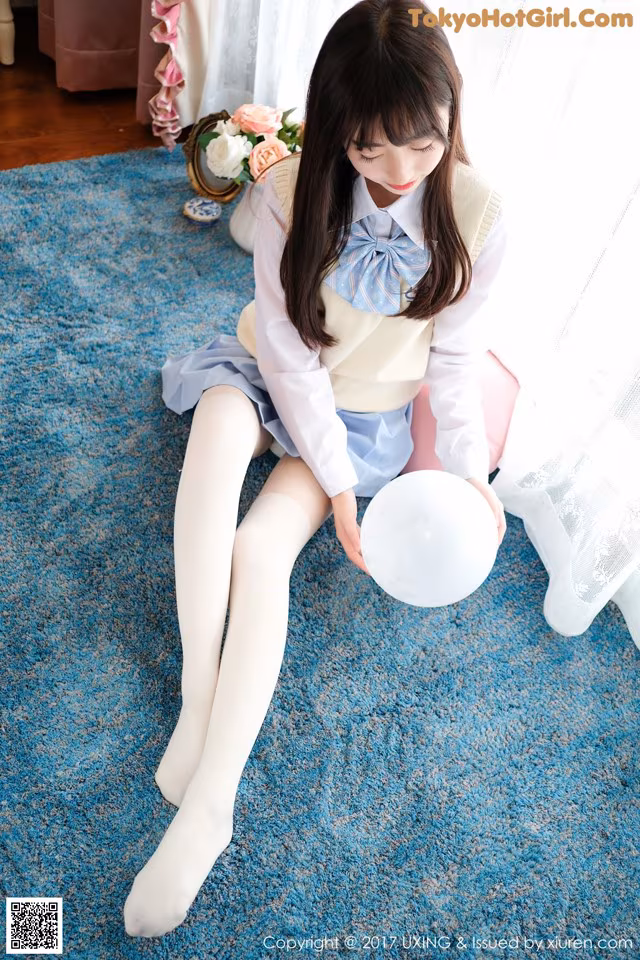 A woman sitting on the floor holding a white balloon.
