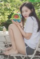 A woman sitting on a chair holding a watermelon.