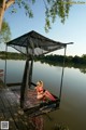 A woman in a red bikini sitting on a dock.