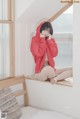 A woman in a red hoodie sitting on a window sill.