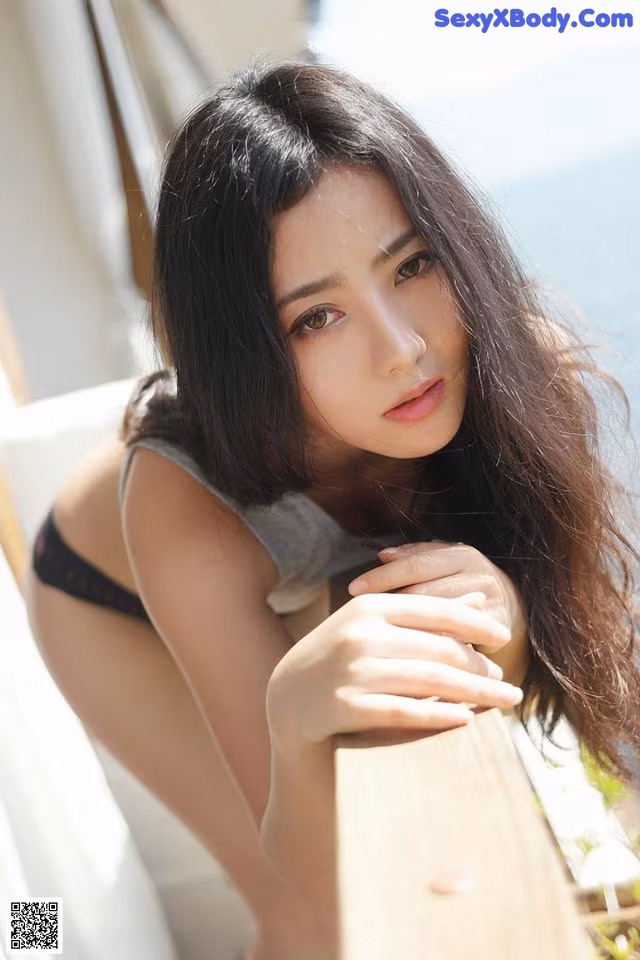 A woman leaning on a railing with her hand on her hip.