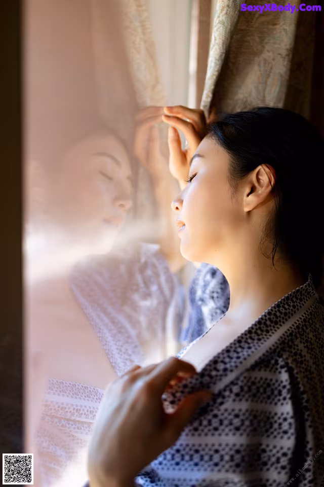 A woman in a kimono looking out of a window.