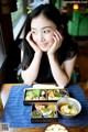 A woman sitting at a table with a bowl of food.