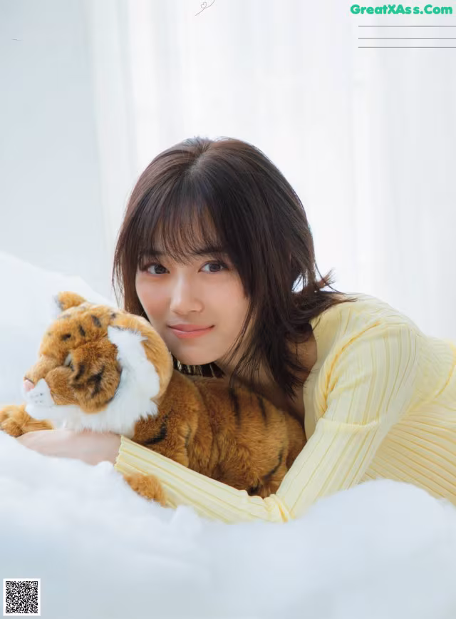 A woman laying on top of a bed holding a stuffed animal.