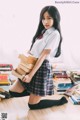 A woman in a school uniform holding a stack of books.