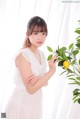 A woman in a white dress holding a lemon.