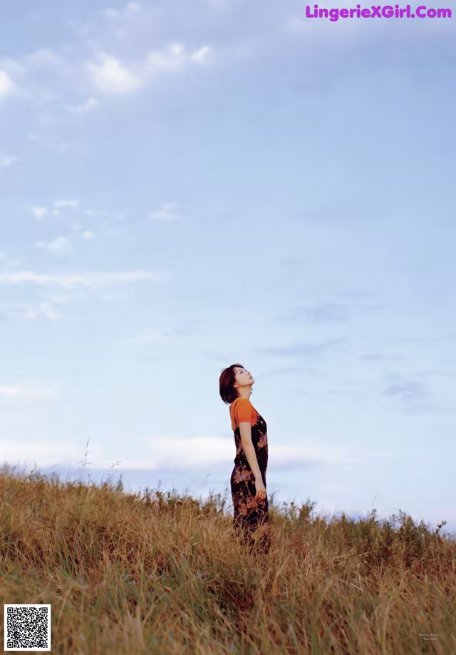 A woman standing in a field of tall grass.