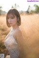 A woman in a white dress standing in a field of tall grass.