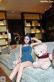 A woman sitting on a couch with a teddy bear.