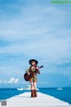 A woman standing on a pier holding a guitar.